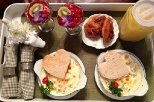 Locally sourced breakfast at the Asheville bnb. Two ceramic dishes with gratins, heart-shaped bread slices, a jug of orange juice, fresh fruits and buns.
