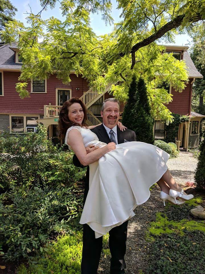 Elopement in Asheville NC. A newly wed couple, the husband is carrying the wife through the backyard garden of the Inn.