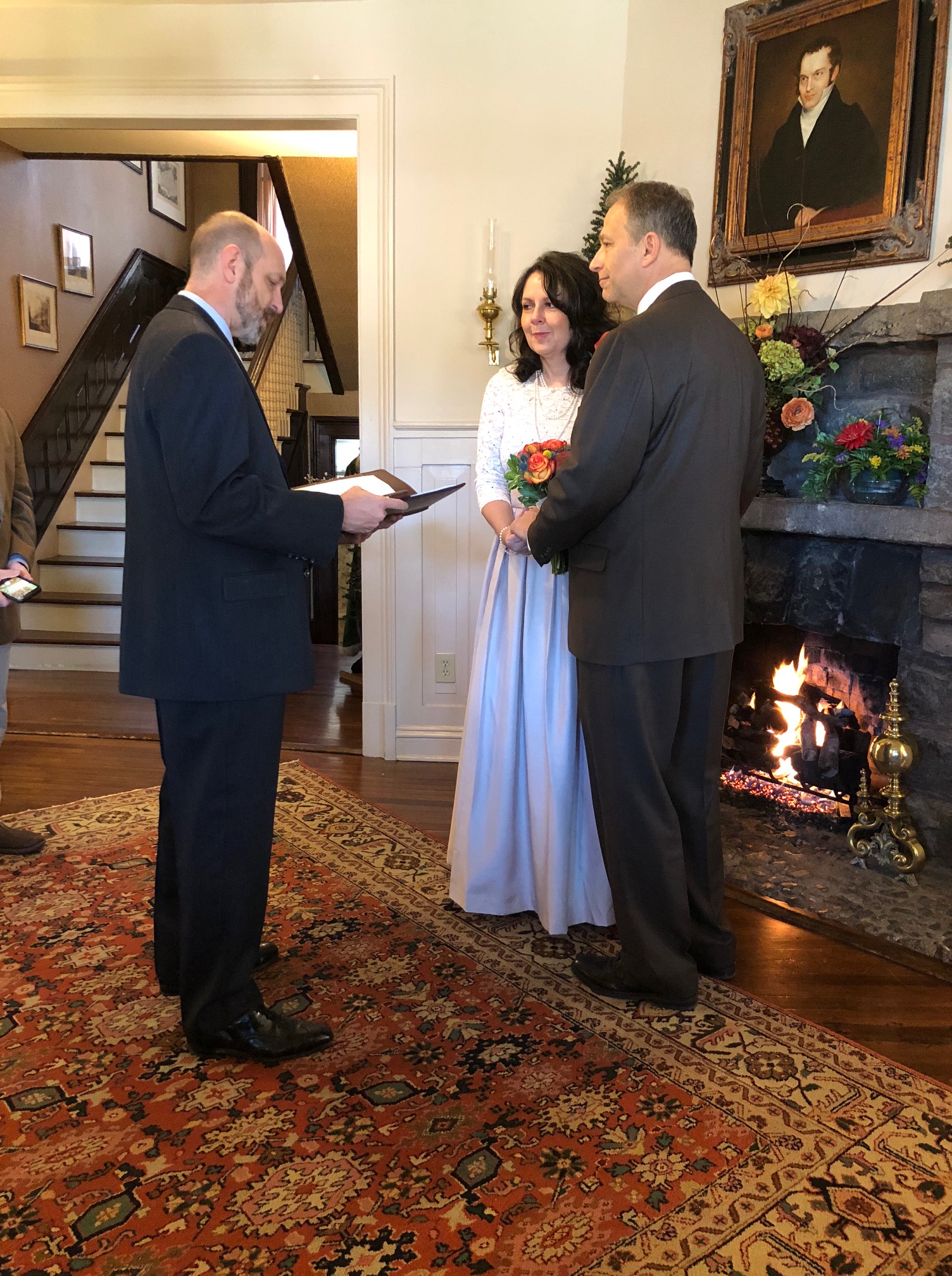 Asheville NC Elopement. A couple holding hands, standing in front of the mantelpiece with an officiant.