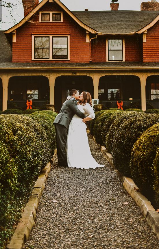 An Asheville elopement. A newly wed couple kissing on the gravel path leading to the front entrance of the Inn on Montford.