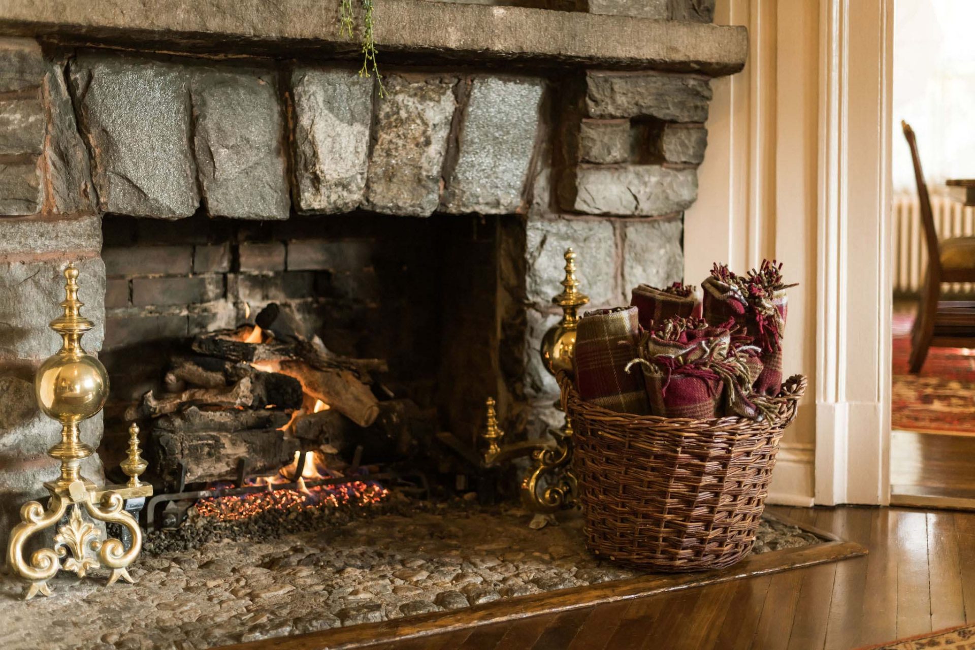 A close-up of a stone fireplace with a woven basket full of blankets