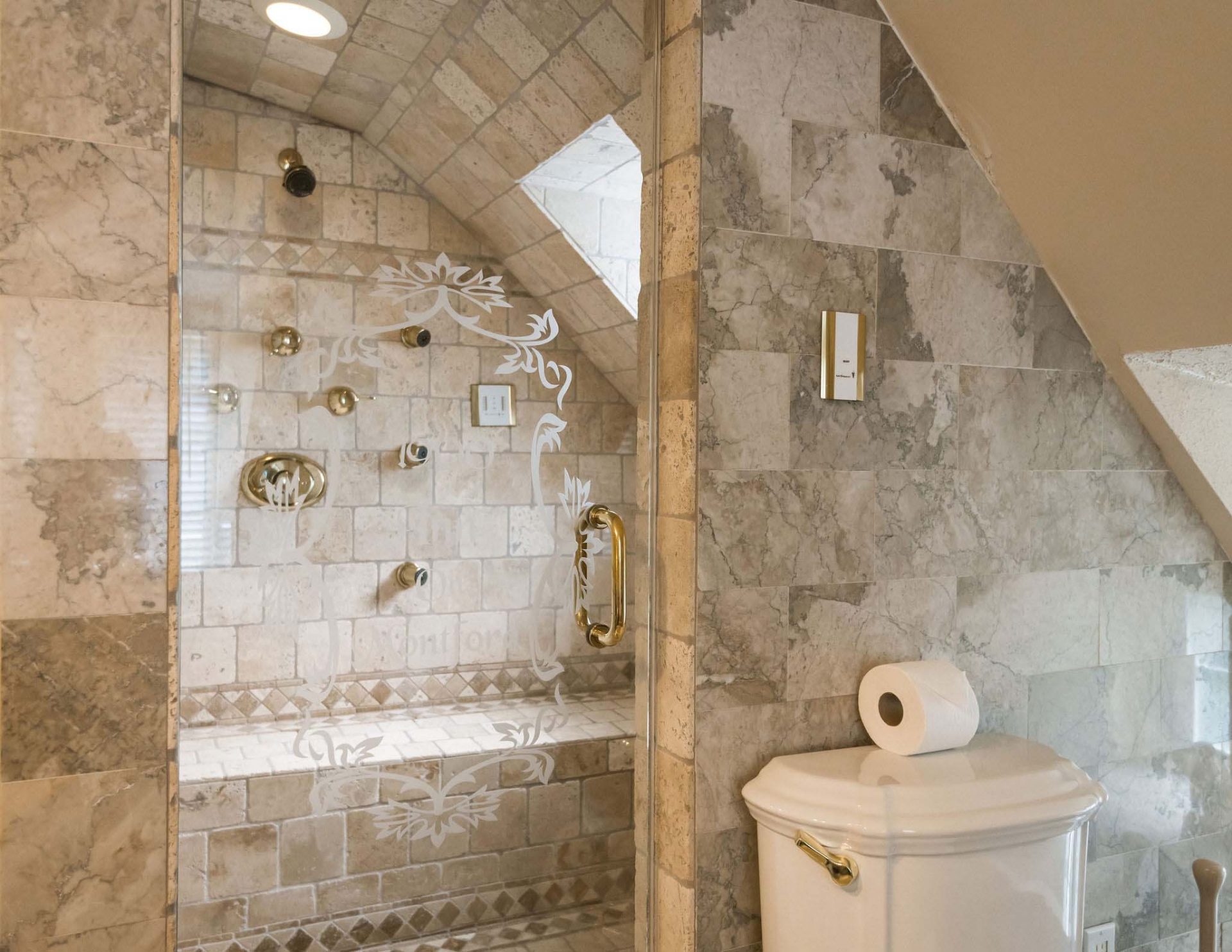 Private bathroom with beige, decorative tiles and a glass door, with a steam shower with multiple body jets.