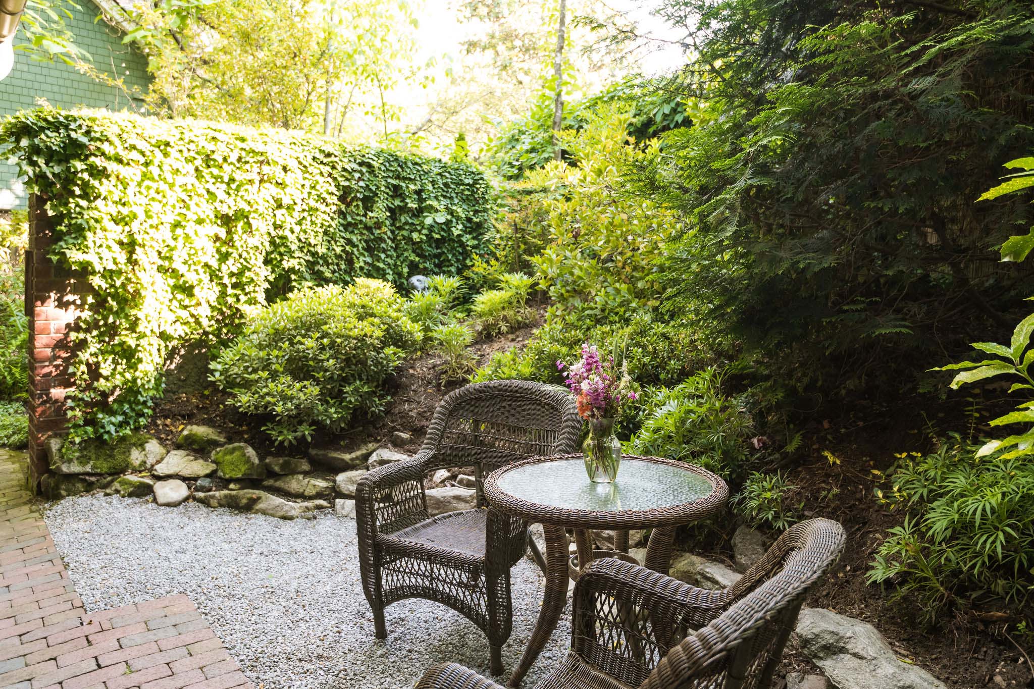 A small, enclosed backyard garden with a private entrance from one of the Asheville bed and breakfast rooms, with two chairs and a table.