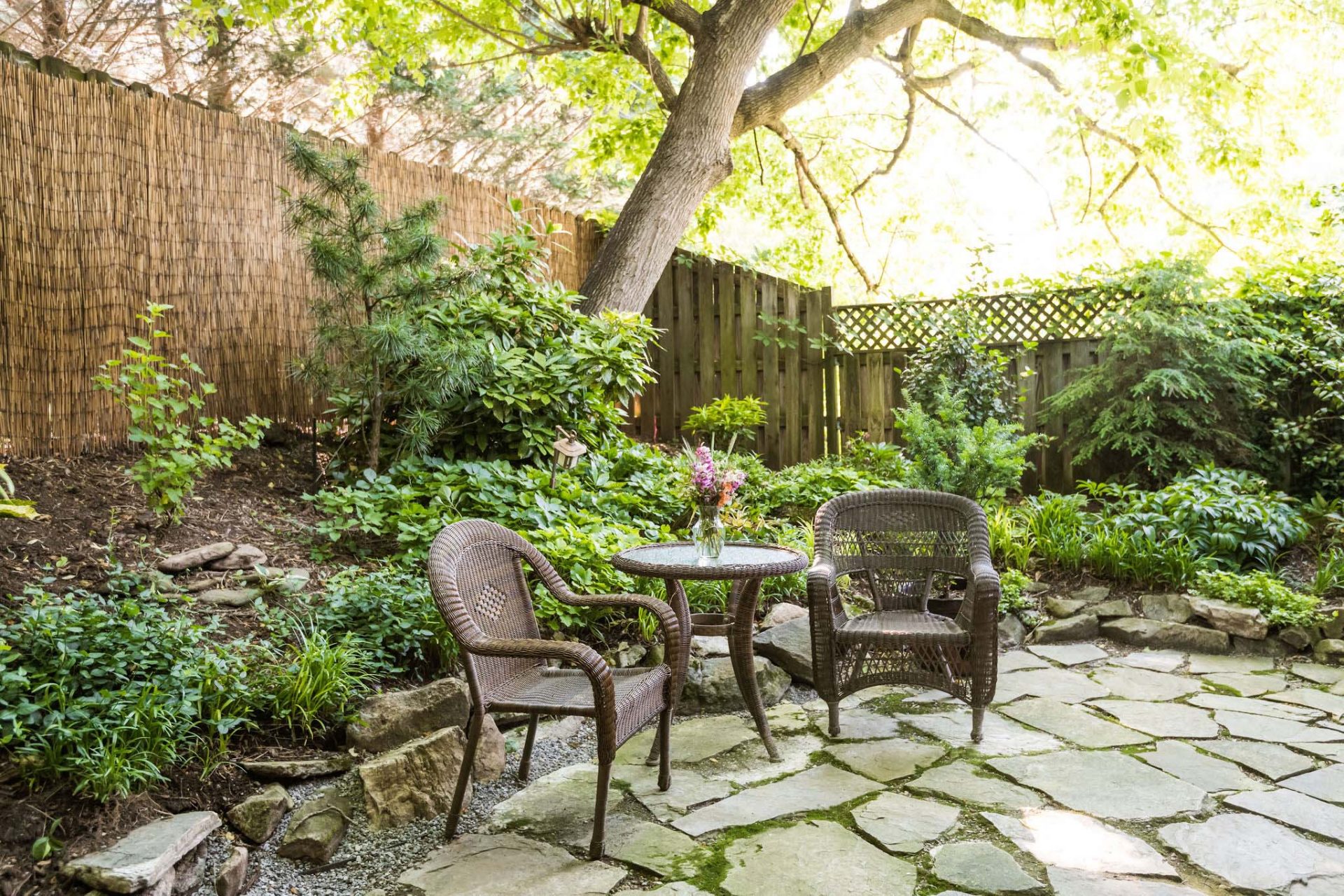 An enclosed rear garden with two rattan airmchairs and a glass table.