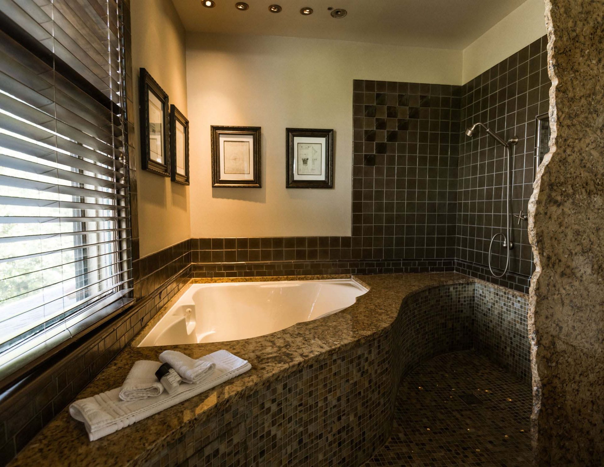 A two-Person jetted airbath tub with chromatherapy lights, marble countertops, and tiled floors. A romantic bath for a romantic Asheville getaway, captured in a dimmed light.