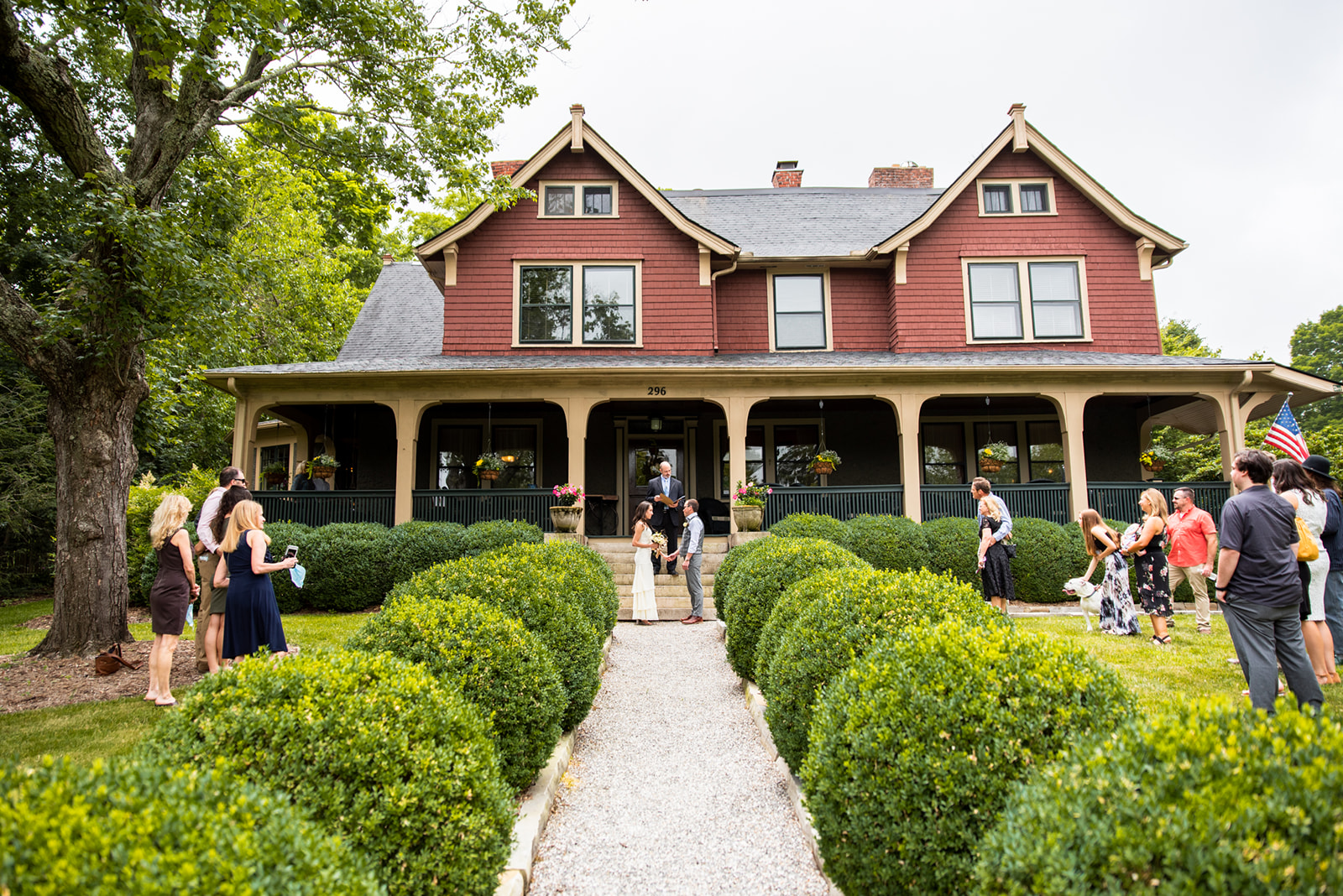 An intimate wedding ceremony at the Asheville bed and breakafst. The couple standing at the feet of the front porch, surrounded by guests scattered across the front yard.