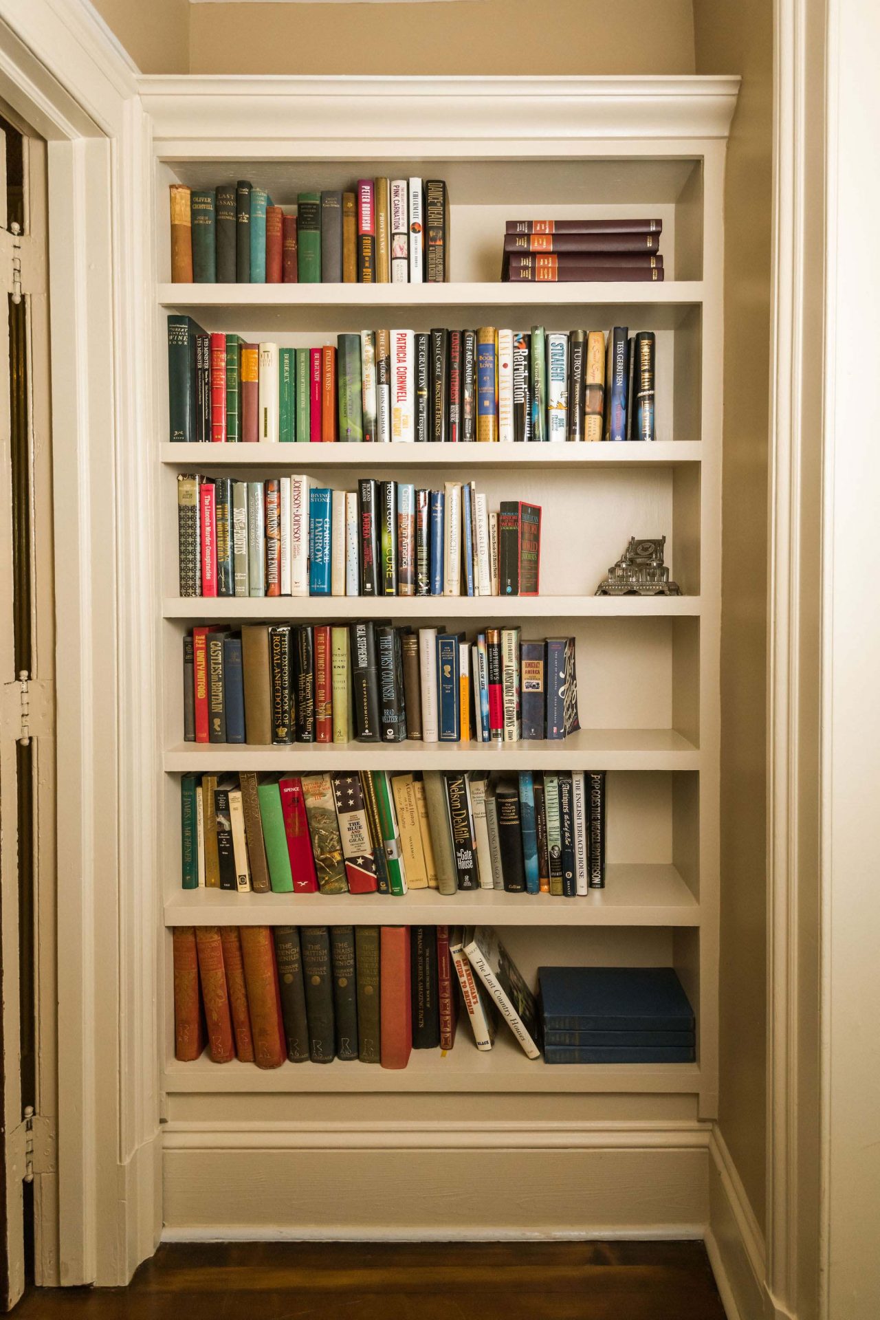 A bright wooden bookcase tucked into a corner of a king bedroom.